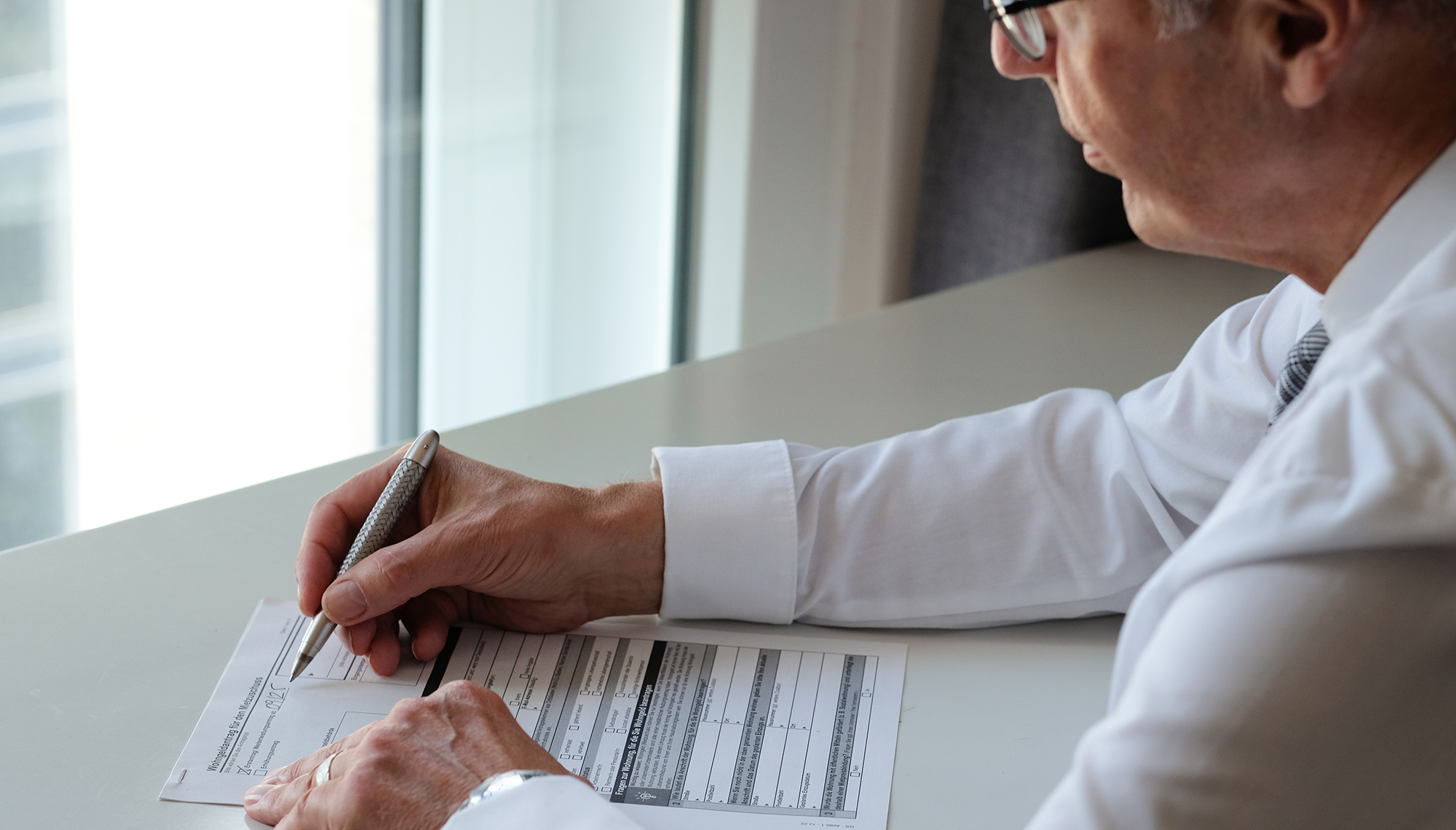 wohngeld-beratung-2 Wohngeld-Berater bei der Wohngeld Beratung in Hamburg: Er sitzt am Schreibtisch und füllt einen Wohngeldantrag aus